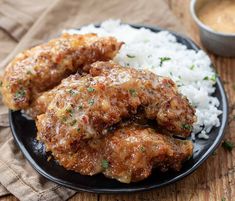 two pieces of fried chicken on a plate with rice and sauce