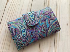 a purple and blue paisley print wallet on a wooden surface