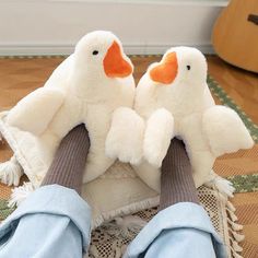 two stuffed ducks sitting on top of each other in front of a person's feet