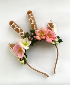 a giraffe headband with pink flowers and leaves on it's side