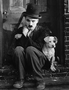 a man sitting on the steps with his dog in front of him wearing a top hat