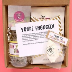 an open box with some items in it on a pink surface and a sign that says you're engaged