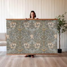 a woman holding up a large piece of fabric with an intricate design on the front