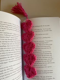 an open book with pink crocheted hearts on the pages and a red tassel