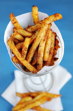 french fries in a glass bowl on a blue surface