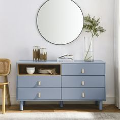 a blue dresser with a round mirror above it