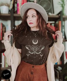 Discover the allure of our Whimsigoth Moth Shirt, blending celestial boho charm with dark academia style. This T-shirt features a geometric moth design, complemented by moon phases, ideal for goth fashion enthusiasts. A whimsical and thoughtful gift for her, it's a unique addition that brings a touch of mystique to any outfit. 🌙🦋  Here's what you need to know  ★ Fit ★ This is a unisex T-shirt. It might be a bit larger than your usual size. So, check out our size chart to find your perfect fit. Want an oversized look? Pick a size larger than you normally would. For a snug fit, go a size down.👕🔍 ★ Fabric ★ We're all about comfort and quality. ● It's lightweight and thin - perfect for summer, with a fabric weight of just 4.2 oz/yd² (142 g/m²). ☀️🍃 ● For solid colors, we use 100% Airlume Goth Whimsical Outfits, Fitted Crew Neck Fairy Grunge T-shirt, Fitted Moon Print Crew Neck Top, Fairy Grunge Tops For Halloween Festival, Fairy Grunge Halloween Festival Tops, Halloween Fairy Grunge Festival Tops, Fairy Grunge Crew Neck T-shirt For Festival, Fairy Grunge Cotton Top For Festivals, Festival Fairy Grunge Crew Neck Top