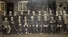 an old black and white photo of men in suits posing for a group photograph with soccer balls