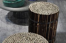 two round tables made out of wood logs and metal bases, one with white pebbles on the top