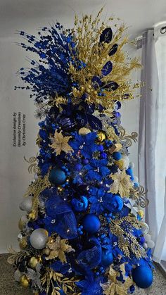 a blue and gold christmas tree with ornaments