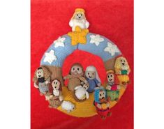 a knitted christmas ornament hanging on a red background with snowmen and sheeps