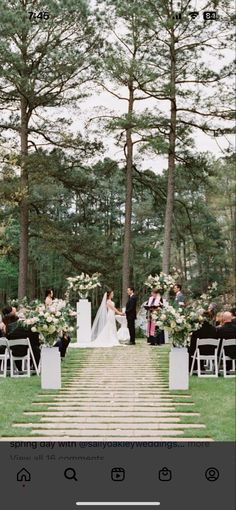 an outdoor ceremony with white flowers and greenery on the aisle, surrounded by tall pine trees