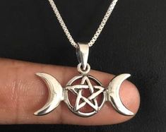 two crescent moon and pentagram pendants on a person's finger