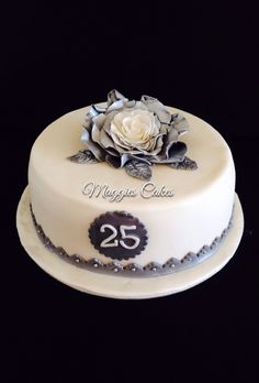 a white cake with silver decorations and a rose on top