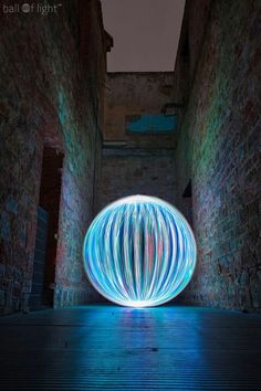 a light painting in the middle of an alleyway with brick walls and blue lights