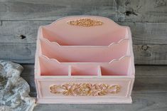 a pink and gold jewelry box sitting on top of a wooden floor