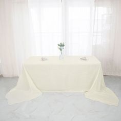 a table with a white cloth draped over it and flowers in a vase on top