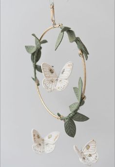 a mobile with three butterflies hanging from it's sides and leaves on the side