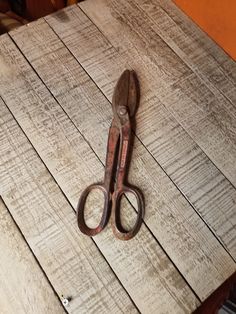 an old pair of scissors sitting on top of a wooden table