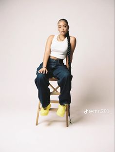 a woman sitting on top of a wooden chair wearing yellow socks and a white tank top