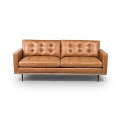 a tan leather couch with wooden legs and an upholstered back, on a white background