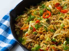 a pan filled with noodles and vegetables on top of a blue checkered table cloth