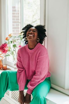 a woman sitting on a window sill smiling