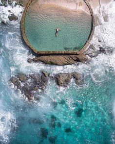 an aerial view of a man standing on the edge of a pier in the ocean