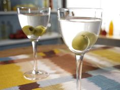 two wine glasses with olives in them on a table