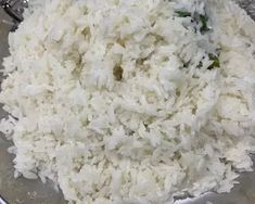 a bowl filled with white rice on top of a wooden table next to a blender