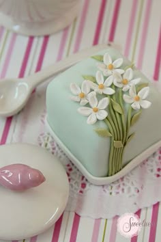 there is a small cake with flowers on it and two spoons next to it