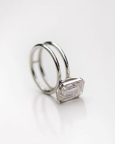 an engagement ring with a baguette cut diamond in the center on a white background