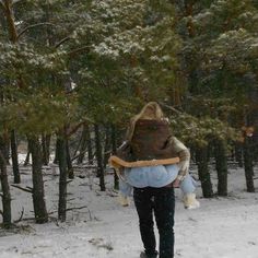 a person walking in the snow carrying a stuffed animal