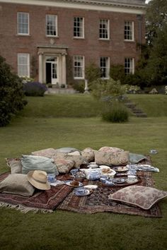 a blanket and pillows on the ground in front of a large brick building with windows