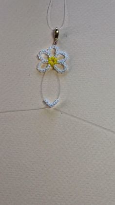 a white and yellow necklace with a flower on it