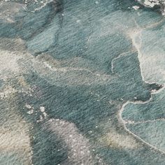 an area rug with blue and green designs on the ground, including watercolors