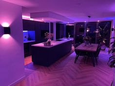 a kitchen and dining room are lit up with purple lighting