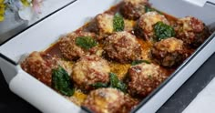 meatballs with sauce and spinach in a white casserole dish