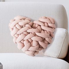 a heart shaped pillow sitting on top of a white couch