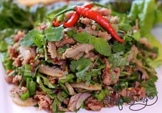 a white plate topped with lettuce, meat and red pepper on top of it