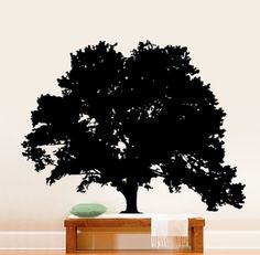 a black tree on top of a wooden table in front of a wall with white walls