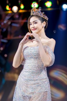 a woman wearing a tiara and posing for the camera at a fashion show with lights in the background