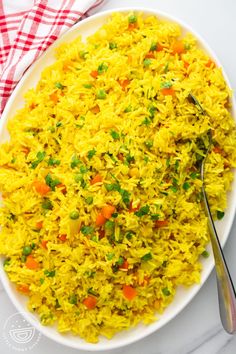 a white plate topped with yellow rice and peas