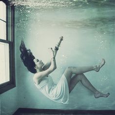 a woman is floating in the water with her legs spread out and feet dangling down