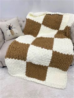 a brown and white blanket sitting on top of a couch next to a gray chair