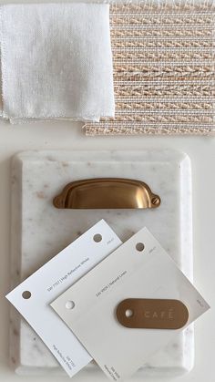 some white and gold items are laying on a marble tray with a metal object in the middle