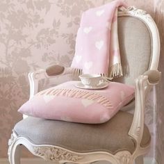 a chair with a pink blanket on top of it next to a wallpapered wall