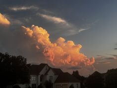 a large cloud looms in the sky over some houses at sunset or sunrise time