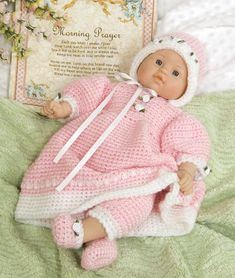 a baby doll laying on top of a bed next to a book