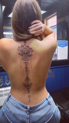 the back of a woman's body with a tattoo on her upper and lower back